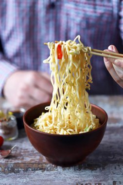 Yemek çubuğuyla erişte yiyen bir adam. Çin eriştesi..