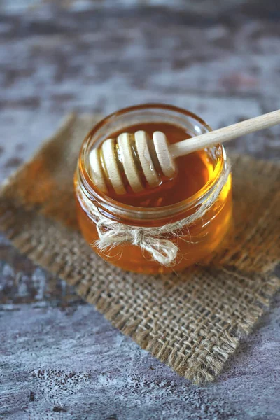 Fresh honey. Jar of flower honey. Stick for honey.