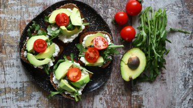 Avokado ve bir tabakta kiraz domatesli sağlıklı tost. Evde diyet yemek..