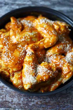 Susam sosunda marine edilmiş çiğ tavuk kanadı..