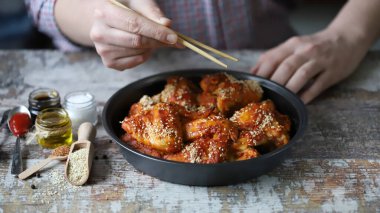 Bir adam elleriyle tavuk kanadı yer. Susam tohumuyla pişirilmiş tavuk kanatları. Bufalo Kanatları.