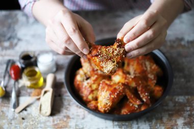 Bir adam elleriyle tavuk kanadı yer..