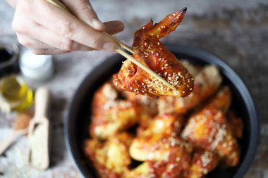 Bir adam elleriyle tavuk kanadı yer. Susam tohumuyla pişirilmiş tavuk kanatları. Bufalo Kanatları.