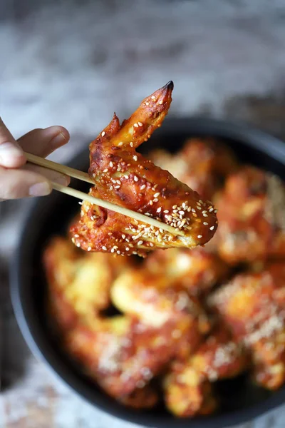 Bir adam elleriyle tavuk kanadı yer. Susam tohumuyla pişirilmiş tavuk kanatları. Bufalo Kanatları.