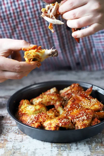 Bir adam elleriyle tavuk kanadı yer..