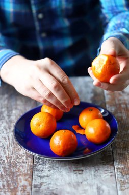 Mandalina soymak. Erkeklerin elleri mandalinayı soyuyor. Tabakta mandalina.