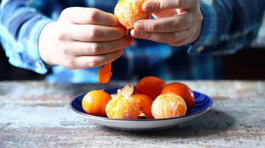 Mandalina soymak. Erkeklerin elleri mandalinayı soyuyor. Tabakta mandalina.