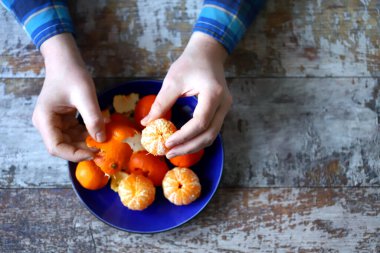 Mandalina soymak. Erkeklerin elleri mandalinayı soyuyor. Tabakta mandalina.