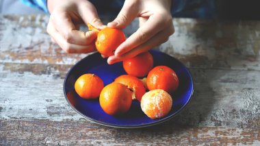 Mandalina soyan bir adam. Mavi bir tabakta mandalina. Şefin elleri mandalina soyar..
