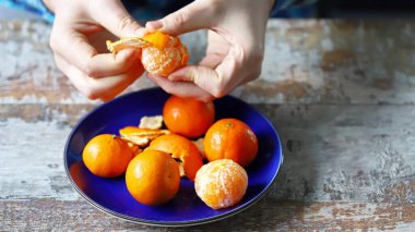 Mandalina soymak. Erkeklerin elleri mandalinayı soyuyor. Tabakta mandalina.