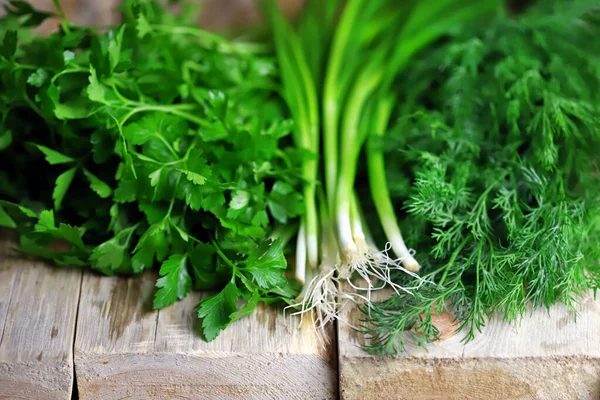 Ahşap yüzeyde taze yeşillikler. Dill, maydanoz, yeşil soğan. Sağlıklı yemek hazırlamak için yeşil otlar..