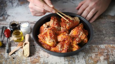 Seçici odaklanma. Çubuklu erkek eli baharatlı tavuk kanadı tutar. Çin usulü tavuk kanadı..