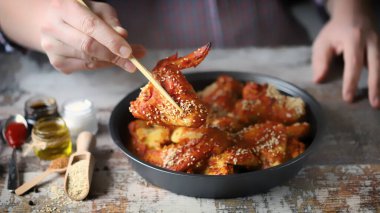 Seçici odaklanma. Çubuklu erkek eli baharatlı tavuk kanadı tutar. Çin usulü tavuk kanadı..