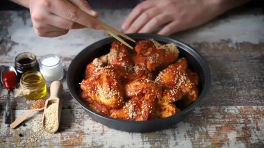 Seçici odaklanma. Çubuklu erkek eli baharatlı tavuk kanadı tutar. Çin usulü tavuk kanadı..