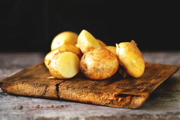 Young raw potato on a wooden surface. Fresh potato harvest.