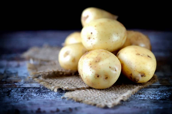 Raw potatoes on a wooden surface. Potato harvest concept.