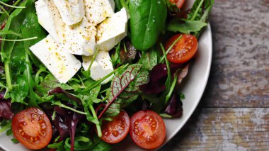 Peynirli ve vişneli domatesli lezzetli salata. Sağlıklı beslenme. Bir tabak salata. Bahar yemeği.