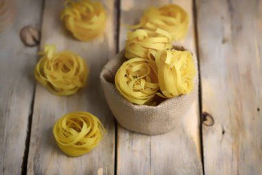 Çiğ fettucine makarna. Ahşap bir yüzeyde makarna yuvaları. Makarna yapıyorum..