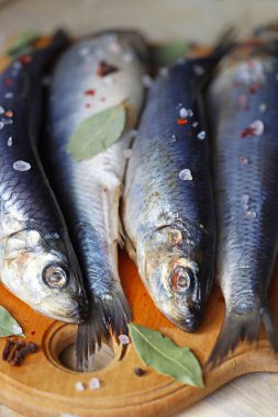 Baharatlı tuzlu ringa balığı. Baharat ve tuz. Tahtada başı ve kuyruğu olan ringa balıkları..