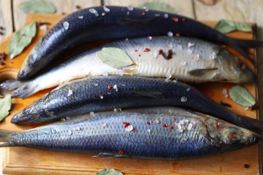 Baharatlı tuzlu ringa balığı. Baharat ve tuz. Tahtada başı ve kuyruğu olan ringa balıkları..