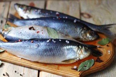 Baharatlı tuzlu ringa balığı. Baharat ve tuz. Tahtada başı ve kuyruğu olan ringa balıkları..