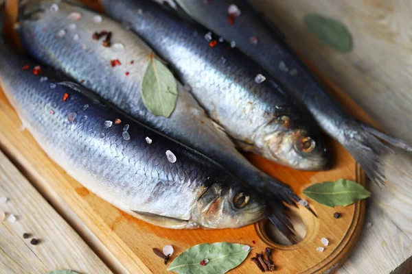Baharatlı tuzlu ringa balığı. Baharat ve tuz. Tahtada başı ve kuyruğu olan ringa balıkları..