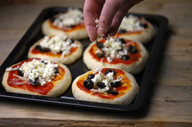 Mini pizza pişiriyorum. Fırın tepsisindeki mini pizzalar..