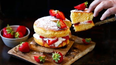 Taze çilek ve kremalı çilekli kek. Victoria keki koyu bir arka planda..