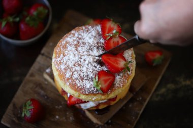 Taze çilek ve kremalı çilekli kek. Victoria keki koyu bir arka planda..