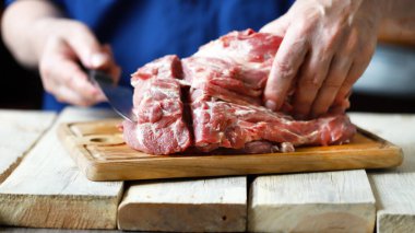 Ahşap bir tahtanın üzerinde şefin ellerinde çiğ et. Et pişiriyorum..