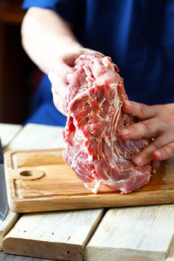 Ahşap bir tahtanın üzerinde şefin ellerinde çiğ et. Et pişiriyorum..