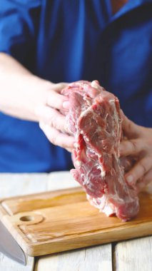 Ahşap bir tahtanın üzerinde şefin ellerinde çiğ et. Et pişiriyorum..