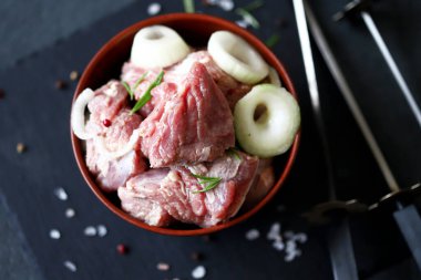 Barbekü pişirme. Et parçaları aşçı tarafından şişte eldiven ile asılıyor. Siyah arkaplanda çiğ kebap.