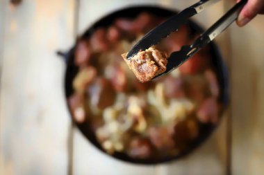 Kızarmış etle kızartma tavası. Adam kızarmış et yiyor..