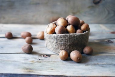 Çuvalda küçük çiğ patates. Yavru patates. Kırsal tarzda. Köylü patatesleri.