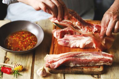 Şef salamuradaki domuz kaburgalarını marine ediyor. Izgara kaburga.