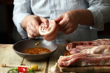 Şef salamuradaki domuz kaburgalarını marine ediyor. Izgara kaburga.