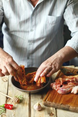 Şef salamuradaki domuz kaburgalarını marine ediyor. Izgara kaburga.