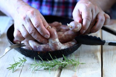 Erkek eller tavaya çiğ sosis koyar. Bavyera sosisi pişirmek.