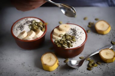Bir kaşık yoğurtla erkek eli. Tohumlu ve muzlu sağlıklı chia yoğurdu..