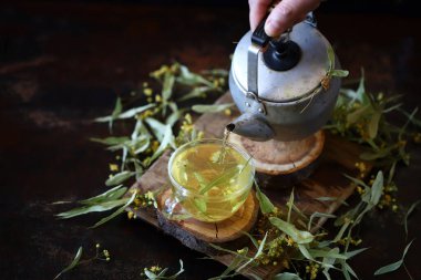 Çaydanlıkta ıhlamur çayı ve koyu arka planda bir fincanda. Linden yaprakları.