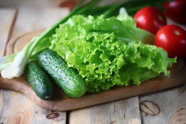 Marul, yeşil soğan, domates, salatalık. Tahtada taze sebzeler. Sağlıklı diyet kavramı.