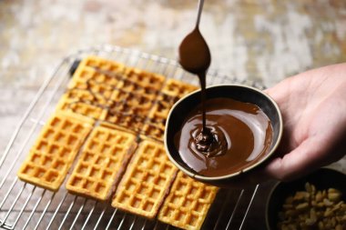 Chocolate poured over waffles. Dessert preparation. French waffles with chocolate.