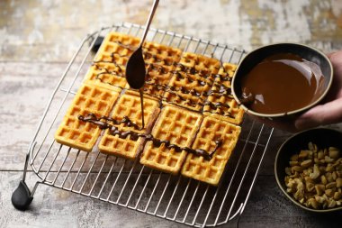 Chocolate poured over waffles. Dessert preparation. French waffles with chocolate.