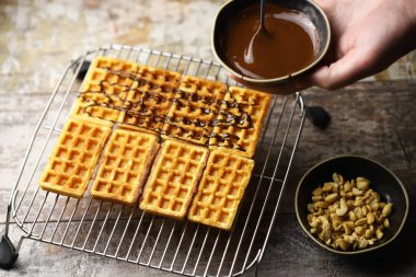 Chocolate poured over waffles. Dessert preparation. French waffles with chocolate.
