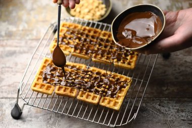 Chocolate poured over waffles. Dessert preparation. French waffles with chocolate.