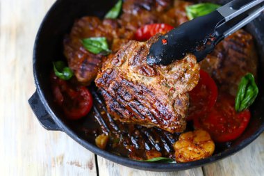 Lezzetli iştah açıcı ızgara biftek. Et için maşa ve biftekli kızartma tavası.