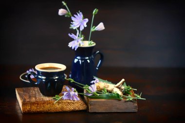 Seçici odaklanma. Kupada hindiba içkisi. Çiçekler ve hindiba yaprakları. Hindiba ile hayat.