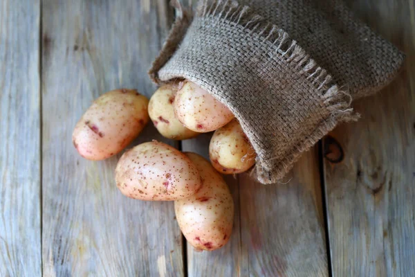 Junge Kartoffeln Einem Sack Auf Einer Holzoberfläche — Stockfoto