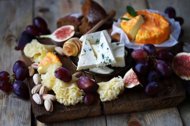 Üzümlü peynir tahtası, incir, fıstık ve bal. Tahtada meyveli farklı peynir türleri.
